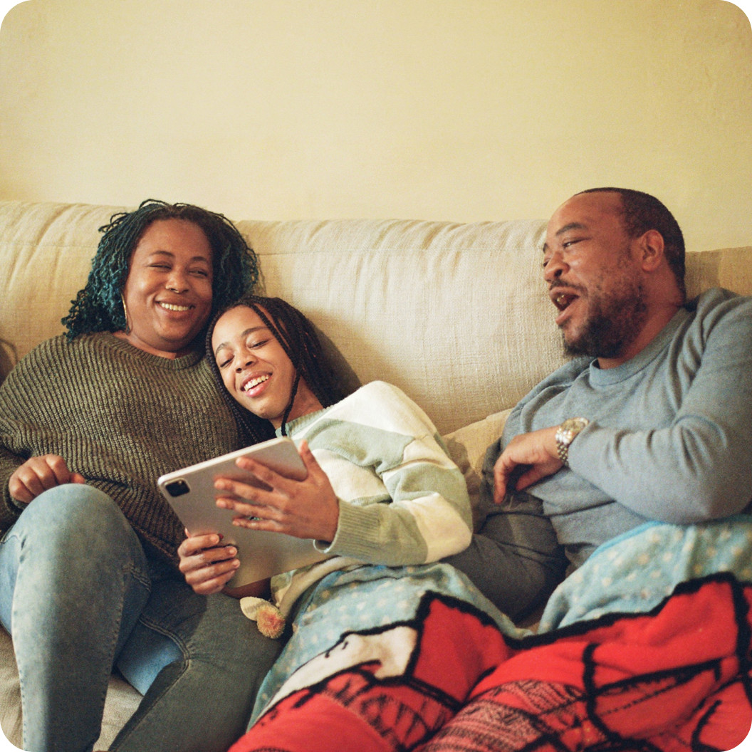 Family relaxing on a couch and using a tablet together, connected with Brightspeed Internet.