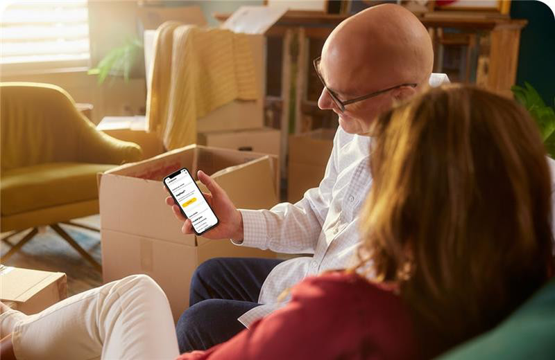 Customer checking Brightspeed app with EasyMove feature on a smartphone during a home move with boxes in the background.