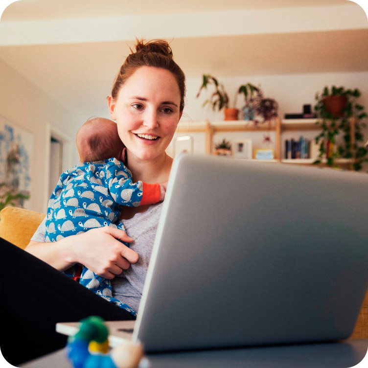 Mom reviewing account information on a laptop while holding a baby, powered by Brightspeed Internet.